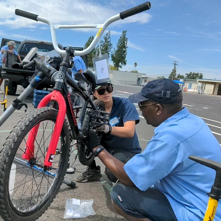 A man and a woman work on a bicycle.