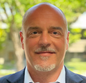 Headshot of a white man with a gray beard and mustache.