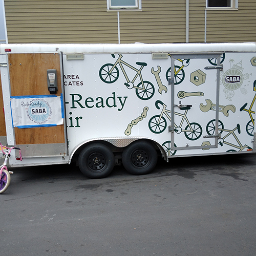 A white van with pictures of bikes and tools on the side.