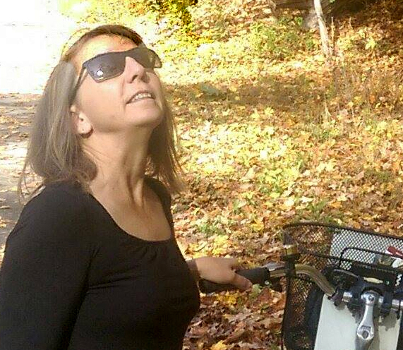 Pamela Dupzyk holds a bike and looks up at the sky.