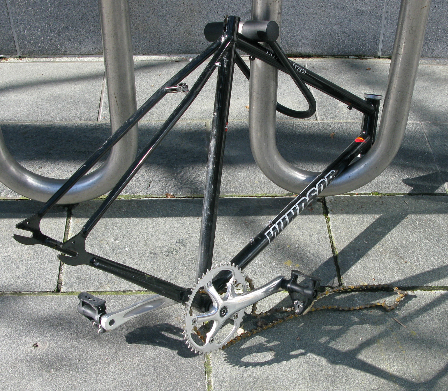 Part of a bike frame locked to a bike rack.