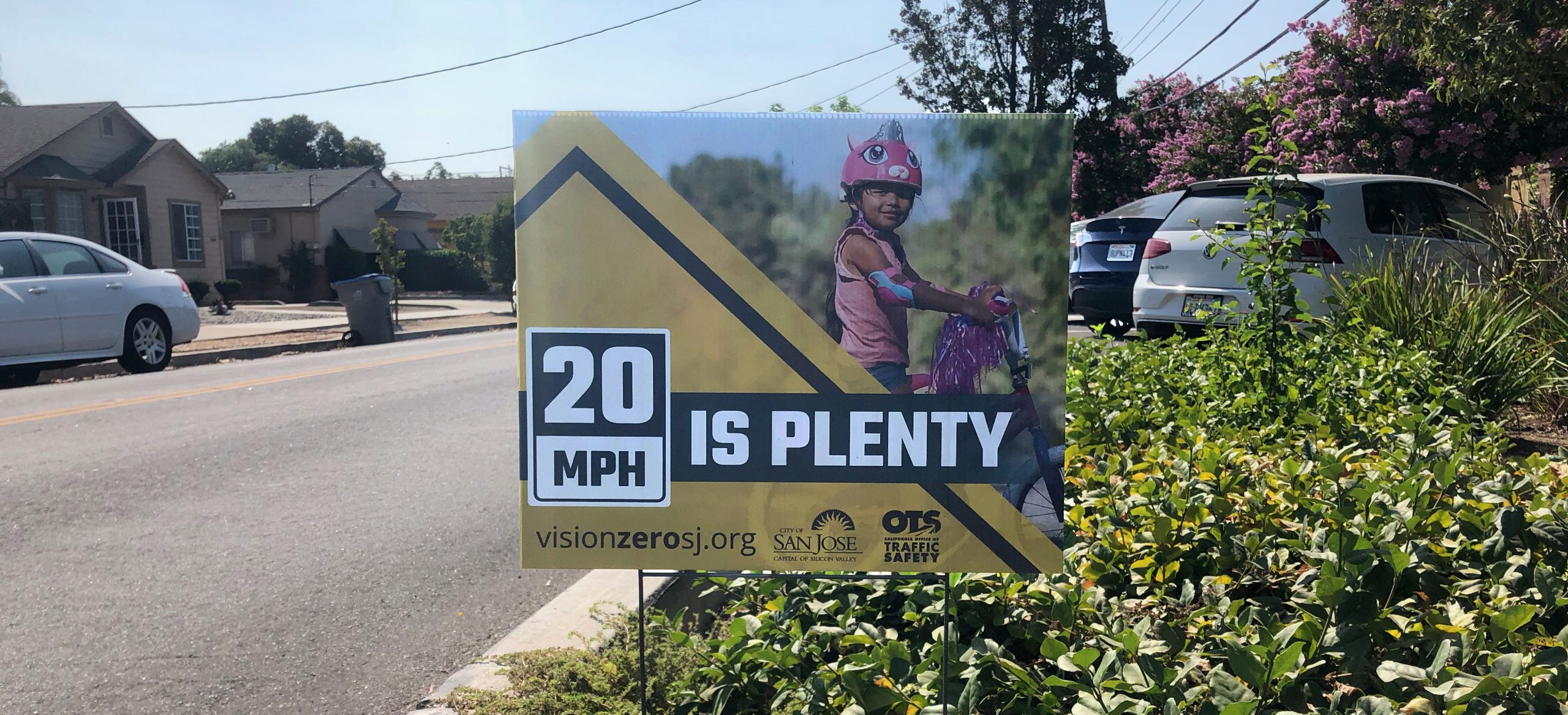 Yard sign with a young girl and her bike - "20mph is Plenty."