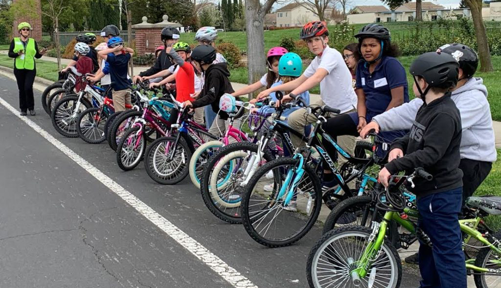 Kids on bikes line up while an adult gives them instruction.