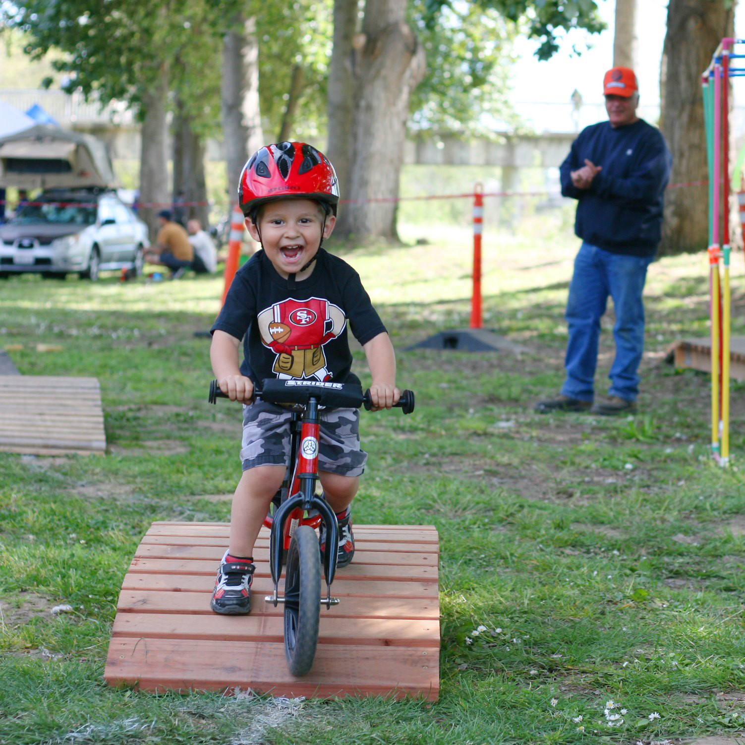 A child rides his bike over a wooden bridge.