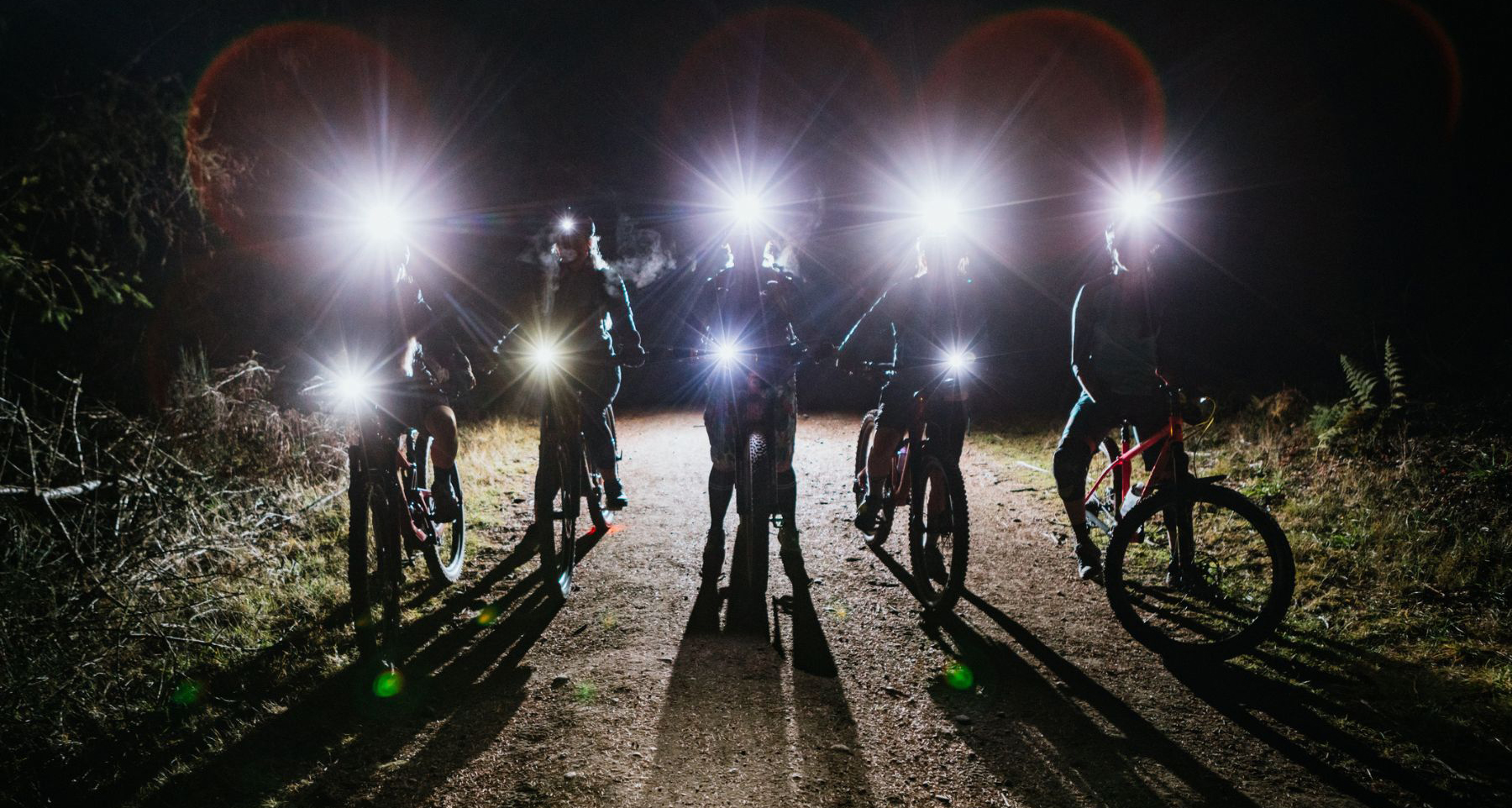 Five cyclists at night with bike lights.