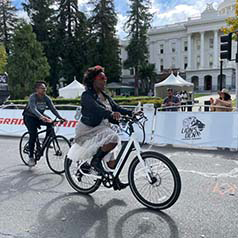 A woman rides a bike past the Sacramento Capitol.