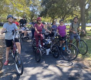 A group of people on bikes on a bike path under trees.