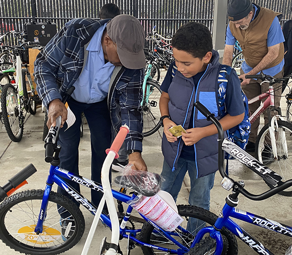 A man adjusts a bike while a boy looks on.