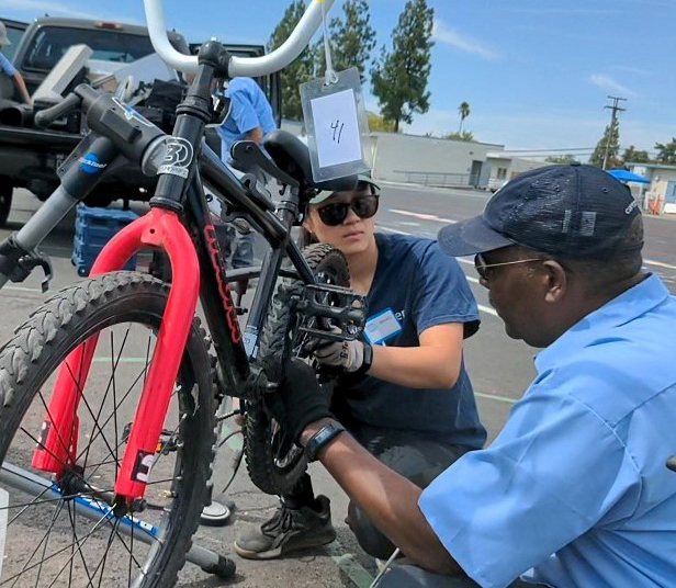 A man and a woman work on a bicycle.