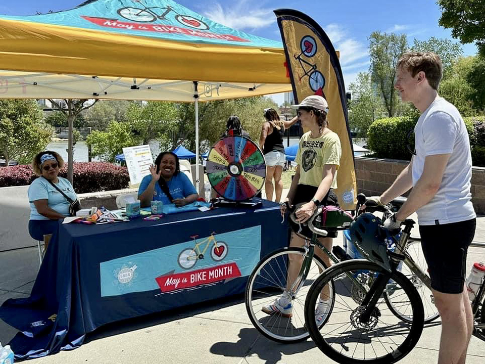 A cyclist stands outside a May is Bike Month booth.