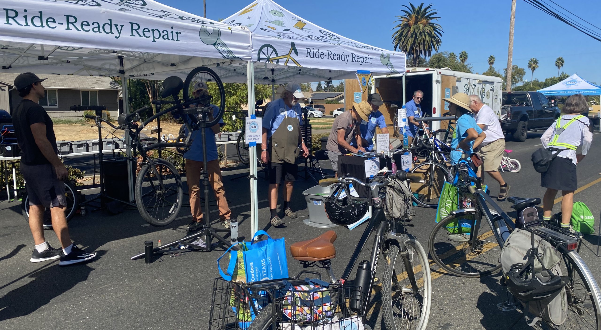 Bikes and people under a canopy that says, "Ride-Ready Repair."