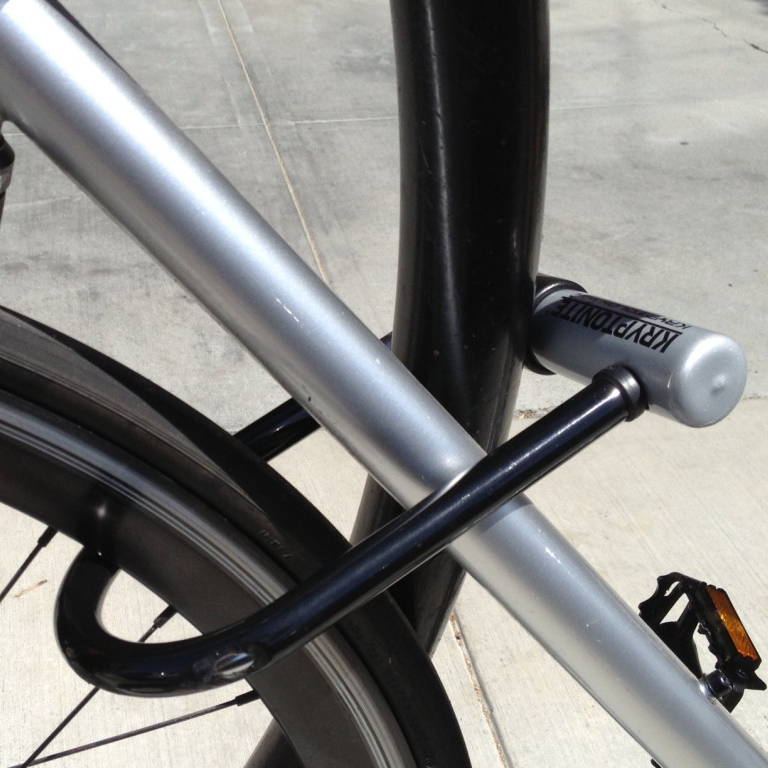 A u-lock secures the frame of a bike to a bike rack.